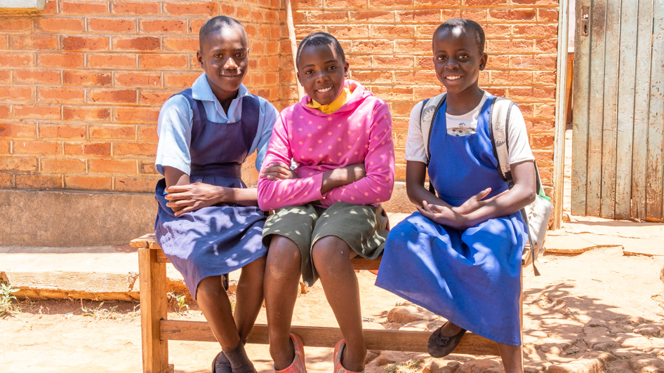 Drei Schulmädchen auf der Bank in Malawi 
