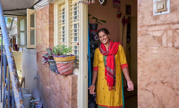 Success story, Kavitha stands in the doorway of her own home